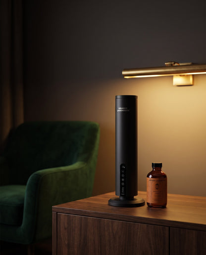 Grande Lavendera Smart App Waterless Aroma Diffuser with 4 oz Moroccan Amber diffuser oil on a walnut console in a lounge at night